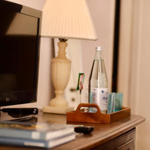einen Schreibtisch mit einem TV und einer Flasche darauf in der Unterkunft La dama con l'ermellino B&B in San Zavedro