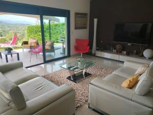 a living room with a white couch and a red chair at Villa Contemporaine Climatisée classée 4 étoiles - Vue panoramique sur la Vallée d'Orb et le Caroux in Bédarieux
