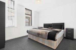 a white bedroom with a bed and two windows at Bradford City Centre One and Two bedroom Apartments CONTRACTORS LONG STAY welcome Parking Available nearby paid in Bradford