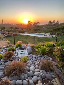 un jardín de rocas con piscina y puesta de sol en Hermosa y acogedora parcela cerca de viñas y playa, en Algarrobo
