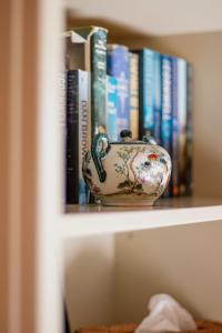 eine Vase auf einem Regal mit Büchern in der Unterkunft Casa Mori House in Stellenbosch