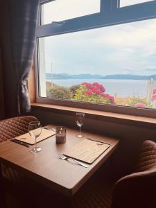 a table with two wine glasses and a window at The Rowanberry Suite at Rowan Cottage in Elgol