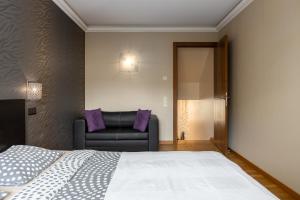 a bedroom with a bed and a leather couch at Jekabpils 2 Apartment in Rīga