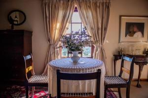 a dining room with a table with a vase of flowers on it at Casa Mori House in Stellenbosch