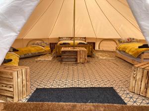 Tienda con 3 camas y mesa. en Roaches Retreat Eco Glampsite - Wallaby Way Bell Tent, en Leek