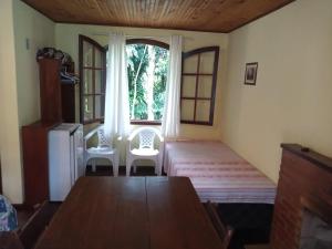 a dining room with a table and chairs and a window at Pousada Sitio dos Pinhais in Visconde De Maua