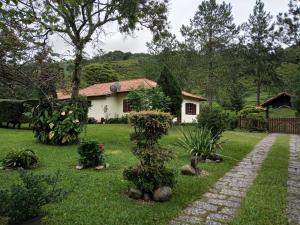 a house in a yard with a pathway and plants at Pousada Sitio dos Pinhais in Visconde De Maua