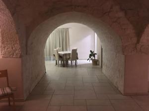 una sala da pranzo con arco, tavolo e sedie di La Valle dei Trulli Relais a Martina Franca