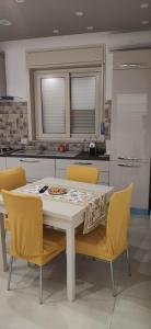 a kitchen with a white table and yellow chairs at Villa Francesca in Catania