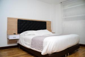 a bedroom with a large bed with a black headboard at HotelSuizaApartamentos in Ipiales