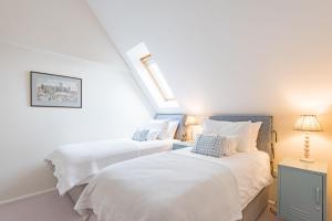 two beds in a room with white sheets at The Loft at Emperor Court by Bloom Stays in Canterbury