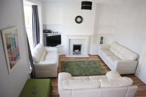a living room with white furniture and a fireplace at Knocking on Gower's Door, Swansea in Swansea