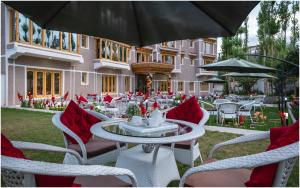 an outdoor patio with tables and chairs with red pillows at Sangaylay palace in Leh +14 photos