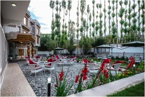 un patio con tavoli, sedie e fiori rossi di Sangaylay palace a Leh