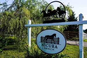 um sinal para um rancho do nirvana com cavalos numa vedação em Nicura Ranch Inn & Stables em Berea