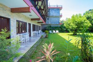 a house with a patio and a yard with chairs at Butterfly Lodge in Pokhara