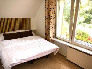 a bedroom with a white bed and two windows at Apartament Natura in Koszalin