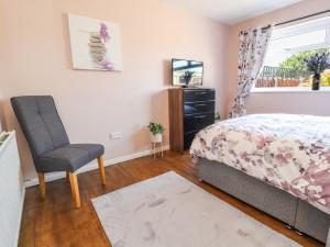 a bedroom with a bed and a chair and a window at The Bungalow in Abergele