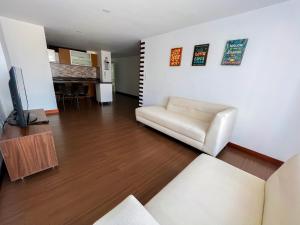 a living room with a white couch and a television at HotelSuizaApartamentos in Ipiales