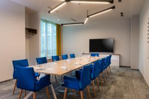 uma sala de conferências com uma mesa longa e cadeiras azuis em Flightgate Munich Airport Hotel, a member of Radisson Individuals em Hallbergmoos
