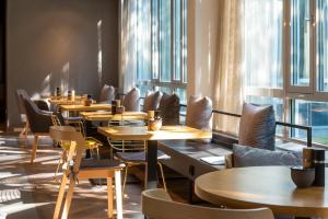 una fila de mesas y sillas en un restaurante con ventanas en Flightgate Munich Airport Hotel, a member of Radisson Individuals en Hallbergmoos