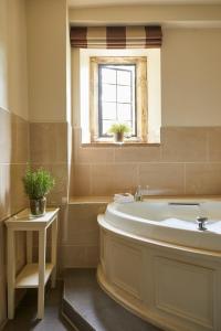a bathroom with a tub, sink and window at The Slaughters Country Inn in Lower Slaughter