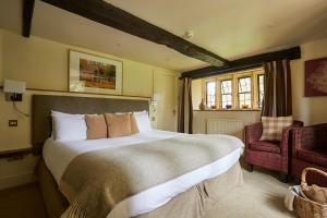a large bed in a room with a large window at The Slaughters Country Inn in Lower Slaughter
