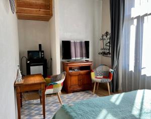 a bedroom with a tv and a desk and chairs at Coté Puy-De dôme in Orcines