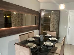 uma sala de jantar com uma mesa preta e cadeiras em Apto luxo e conforto suíte mais dormitório com churrasqueira em Balneário Camboriú