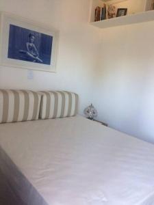 un letto bianco in una camera da letto con una foto sul muro di Apartamento aconchegante perto da praia a Caraguatatuba