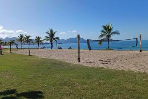 una rete da pallavolo su una spiaggia con palme di Apartamento aconchegante perto da praia a Caraguatatuba