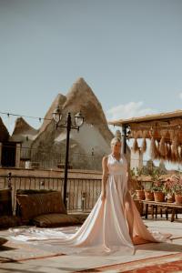 una mujer con un vestido de novia delante de las pirámides en Goreme Valley Cave House, en Göreme