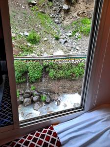 a window with a view of a garden from a room at Blue Water Resort Kalam in Kārandūkai