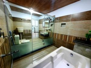 a bathroom with a tub and a shower and a sink at Blue Water Resort Kalam in Kārandūkai