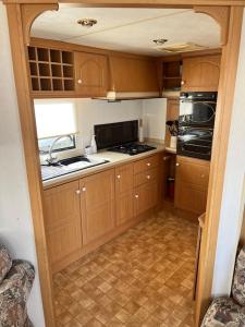 a small kitchen with wooden cabinets and a stove at Central Ingoldmells, Seaview 6 berth in Ingoldmells
