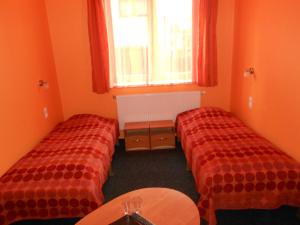 2 camas en una habitación con paredes de color naranja y ventana en Jeruzale Hotel en Vilna