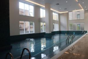 a large swimming pool with chairs in a building at Living Sensory 1-bed rental apartment unit with Pool in Lahore