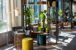une chambre avec des plantes, des chaises et des fenêtres dans l'établissement Flightgate Munich Airport Hotel, a member of Radisson Individuals, à Hallbergmoos