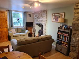 uma sala de estar com um sofá e uma lareira de pedra em North Wales Cosy Cottage with views near Eryri Snowdonia em Nantlle