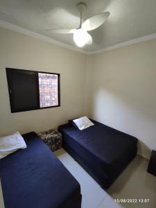 a bedroom with two beds and a tv on the wall at Casa de Férias Praia Grande in Praia Grande