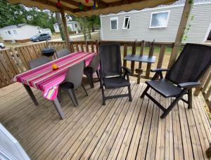 a patio with a table and chairs on a deck at Mobilhome Santerre in Châtillon-sur-Broué
