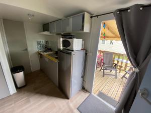 a small kitchen with a refrigerator and a balcony at Mobilhome Santerre in Châtillon-sur-Broué