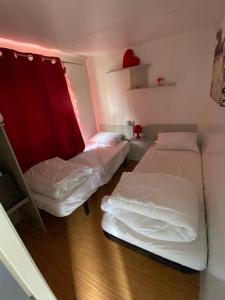 Habitación con 2 camas y cortina roja. en Mobilhome Santerre, en Châtillon-sur-Broué