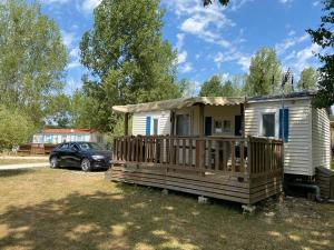 a tiny house with a porch and a car at Mobilhome Santerre in Châtillon-sur-Broué
