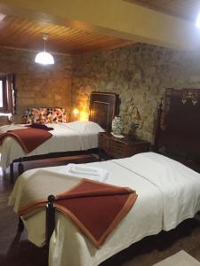 um quarto com 2 camas e uma parede de pedra em Casa do Castelo de Celorico em Celorico da Beira