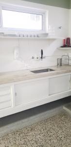 a white kitchen with a sink and a window at Jardim Secreto in Sao Paulo