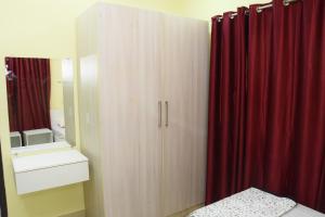 1 dormitorio con armario de madera y cortina roja en SWEET HOMES, en Hyderabad