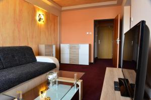 a hotel room with a couch and a tv at Hotel Ďumbier in Brezno