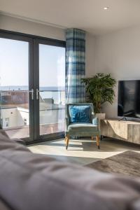 a blue chair in a living room with a large window at 8 Challacombe - Luxury Apartment at Byron Woolacombe, only 4 minute walk to Woolacombe Beach! in Woolacombe