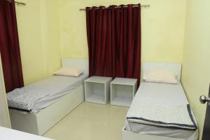 two beds in a room with a red curtain at SWEET HOMES in Hyderabad